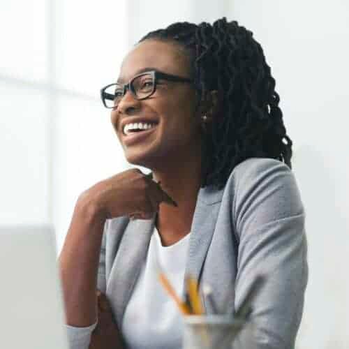 african-american-businesswoman-laughing-sitting-against-window-in-office