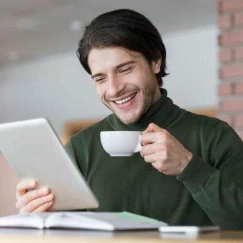 young-successful-businessman-checking-emails-while-having-morning-coffee